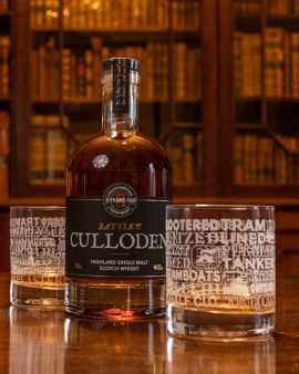 On a table in a library, a bottle of Battle of Culloden whisky in a curved shape with a label 'Highland Single Malt Scotch Whisky. 8 years old.' There are two whisky glasses in front and behind the bottle.
